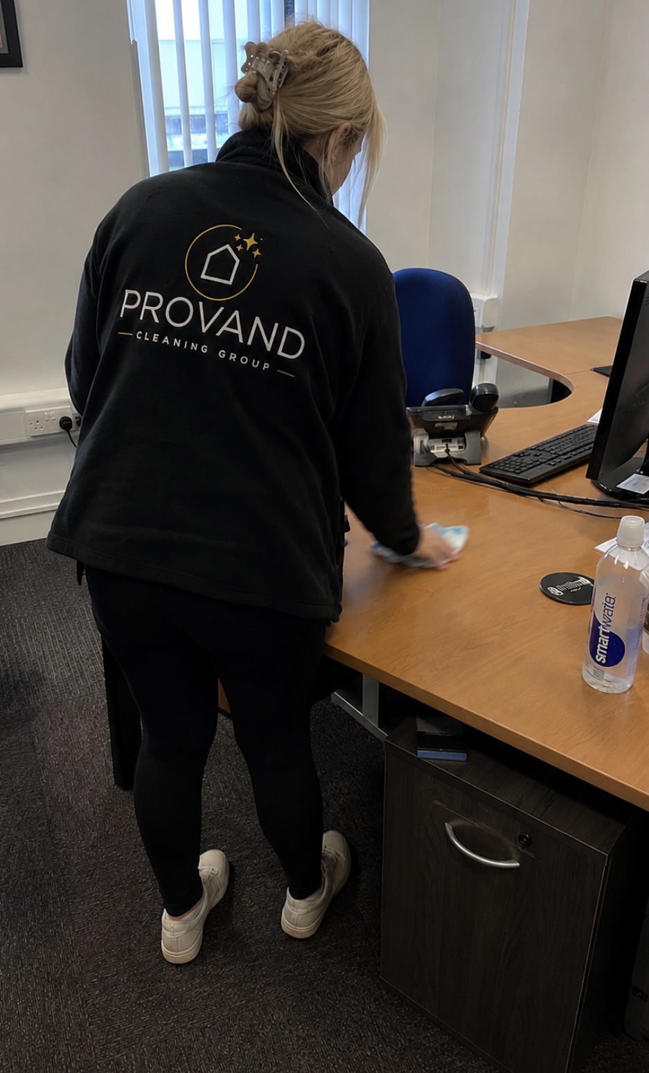 Provand cleaner in uniform wiping an office desk